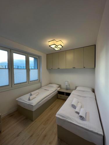 two beds in a room with two windows at Elbląska Noclegi in Łódź