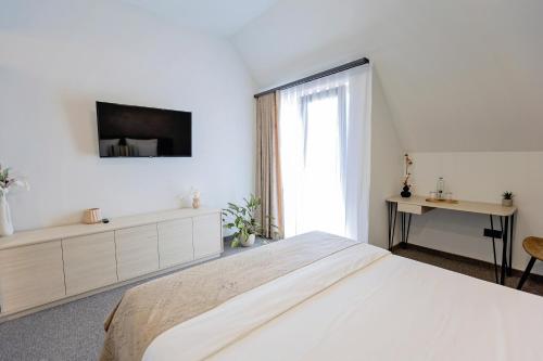 a white bedroom with a large bed and a tv at Complex Acom in Baile Felix