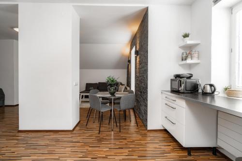 a kitchen with white counters and a table with chairs at Beautiful Apartments With Parking In a Quiet Location in Ostrava