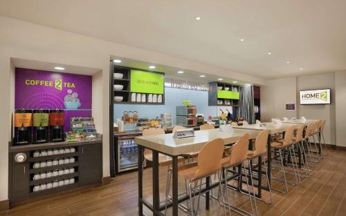 a restaurant with a bar with chairs and a counter at Home2 Suites by Hilton Tuscaloosa Downtown University Boulevard in Tuscaloosa