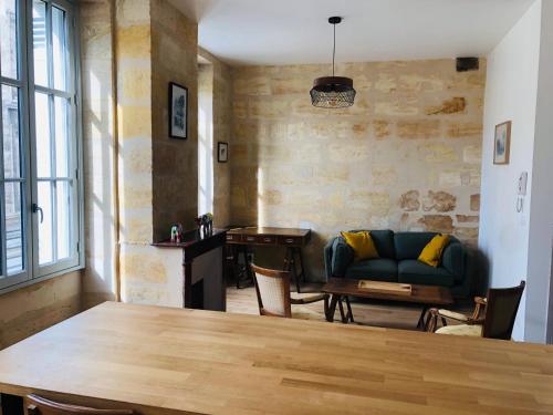uma sala de estar com uma mesa e um sofá em La Pomme d'Or em Bordéus