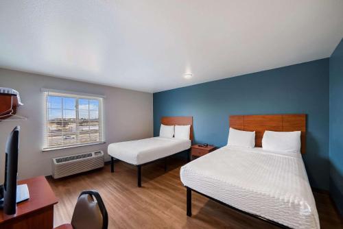 a bedroom with two beds and a desk and a television at WoodSpring Suites Fort Worth Fossil Creek in Fort Worth