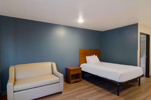 a bedroom with a bed and a chair at WoodSpring Suites Jacksonville I-295 East in Jacksonville