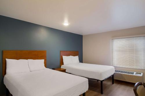 a hotel room with two beds and a window at WoodSpring Suites Jacksonville I-295 East in Jacksonville