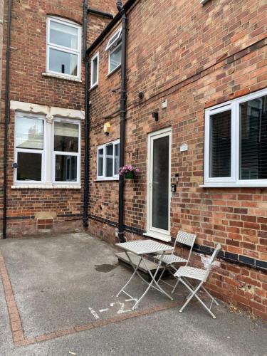 two chairs and a table in front of a brick building at G-Floor Flat with 2 beds, 2 bathrooms, slips 4-6 in West Bridgford
