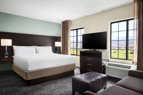 duży pokój hotelowy z łóżkiem i telewizorem w obiekcie Homewood Suites by Hilton Cathedral City Palm Springs w mieście Cathedral City