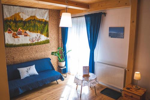 a living room with a blue couch and a window at Jałowcówka Centrum Aktywności Psychoruchowej in Koszarawa