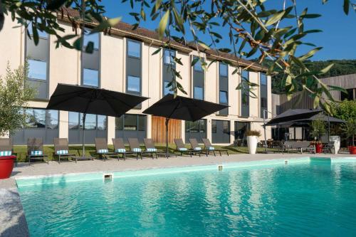 a swimming pool with umbrellas and chairs and a building at Domaine de Charmeil in Saint-Quentin-sur-Isère