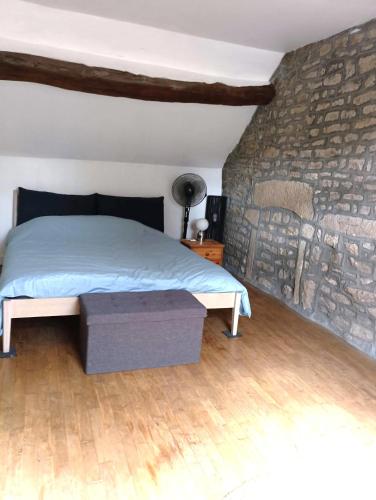 une chambre avec un lit et un mur en pierre dans l'établissement Cottage reflet de bonheur, à Saint-Pierre-Bellevue