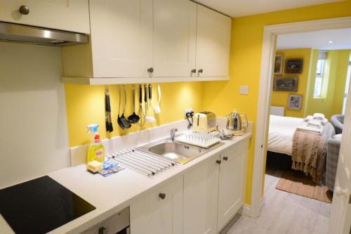 cocina con paredes amarillas, lavabo y cama en The Jericho Studio en Oxford