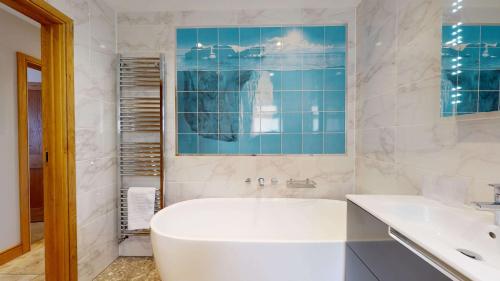 a white bathroom with a tub and a sink at Meadow View in Crawley