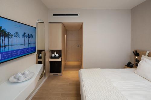 a bedroom with a white bed and a television on the wall at Gai Beach Hotel in Tiberias