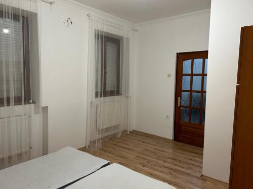 um quarto vazio com paredes brancas e uma porta de madeira em M35 4s Debrecen Apartman em Debrecen