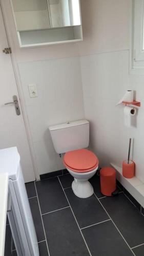 La salle de bains est pourvue de toilettes et d'un couvercle rouge. dans l'établissement le balcon d'Amiens, à Amiens