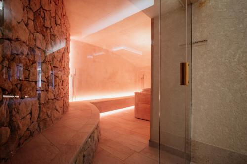 a bathroom with a walk in shower next to a stone wall at Poiano Garda Resort Appartamenti in Garda