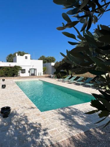 ein Pool mit Stühlen und ein Haus im Hintergrund in der Unterkunft Le Lamie di Ostuni in San Michele Salentino