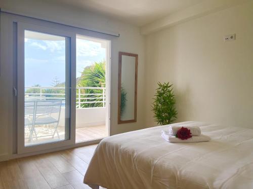 - une chambre avec un lit et une porte coulissante en verre dans l'établissement La Caleta By Gloove, à La Vila Joiosa