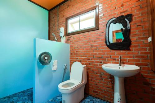uma casa de banho com um WC, um lavatório e uma parede de tijolos em ชานไม้ รีสอร์ท 