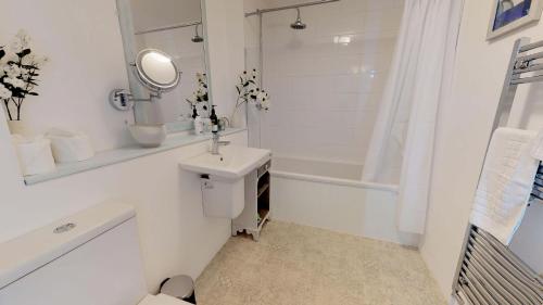 a white bathroom with a sink and a bath tub at Thames View In Oxford in Oxford