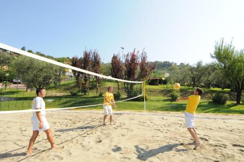 three men playing a game of volleyball on a beach at Poiano Garda Resort Appartamenti in Garda