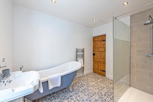 a bathroom with a tub and a shower and a sink at Bay Cottage in Malpas