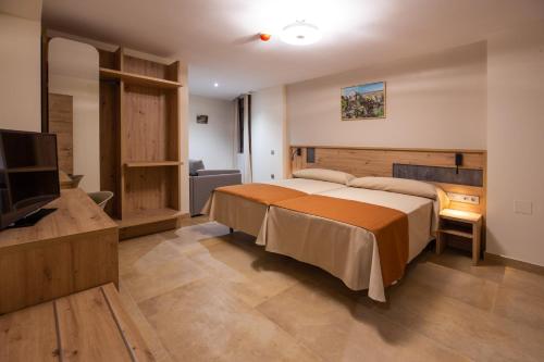 a bedroom with a bed and a flat screen tv at Hostal Las Grullas in Tornos