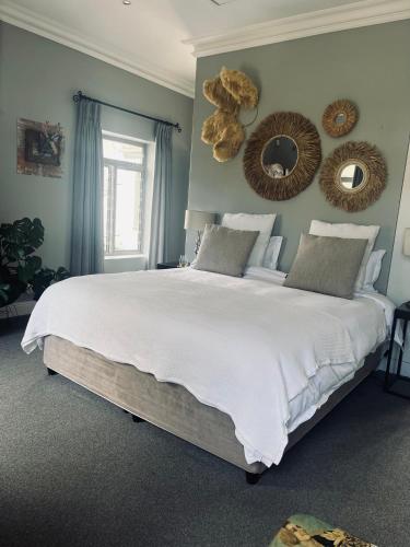 a bedroom with a large white bed with mirrors on the wall at Esme Road - WE HAVE NO LOADSHEDDING! in Cape Town