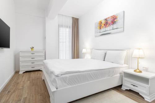 1 dormitorio blanco con 1 cama blanca y TV en Crisana Flats, en Oradea