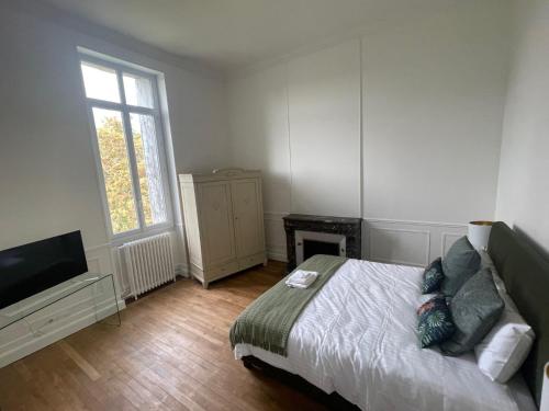 um quarto com uma cama, uma televisão e uma janela em Château de Respide em Langon