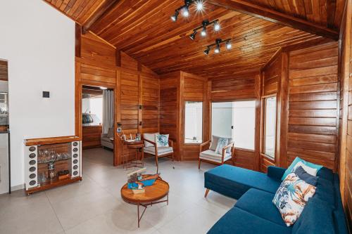 a living room with a blue couch and wooden walls at casadecastelhanos, Quadra do MAR de CASTELHANOS, 4 suítes com AR, Churrasqueira, Piscina, Hidromassagem, Cozinha INTEGRADA GOURMET Ideal para FAMÍLIA E AMIGOS in Anchieta
