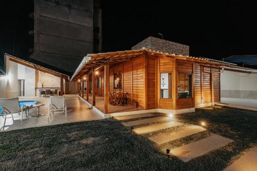 a small wooden house with a patio at night at casadecastelhanos, Quadra do MAR de CASTELHANOS, 4 suítes com AR, Churrasqueira, Piscina, Hidromassagem, Cozinha INTEGRADA GOURMET Ideal para FAMÍLIA E AMIGOS in Anchieta