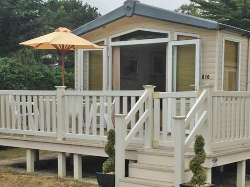a small house with a porch and an umbrella at Hoburne park Bluebell10 in Burton