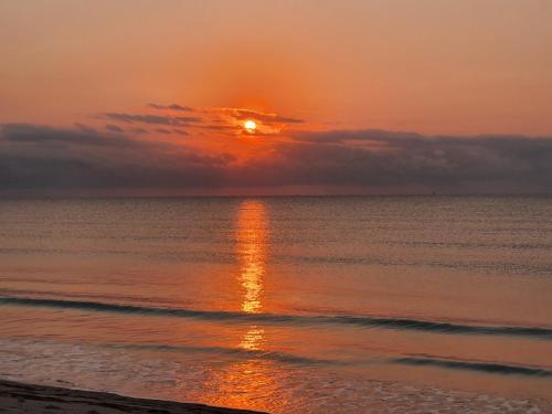 a sunset on the beach with the sun setting at Mahali Maalum Barefoot Lodge in Mkwaja