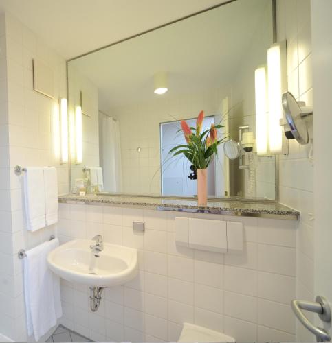 a white bathroom with a sink and a mirror at Nordsee Hotel Fischereihafen in Bremerhaven