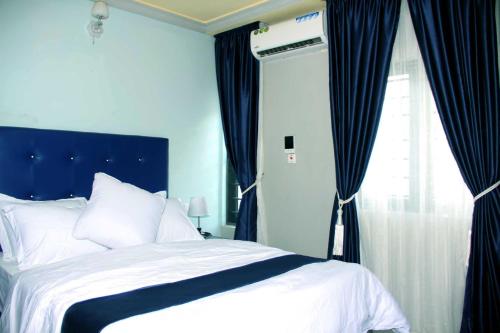 a bedroom with a bed with blue curtains and a window at SILVERZB RESORT in Iseyin