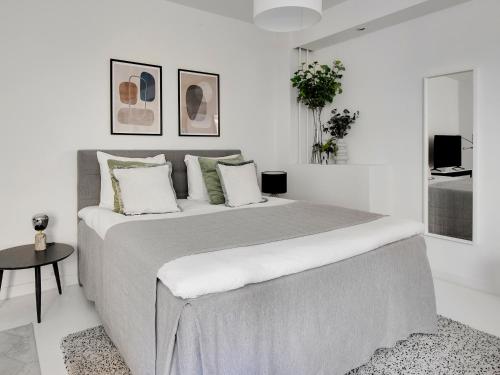 a white bedroom with a large bed and a table at Sanders City - Spacious studio apartment in Copenhagen