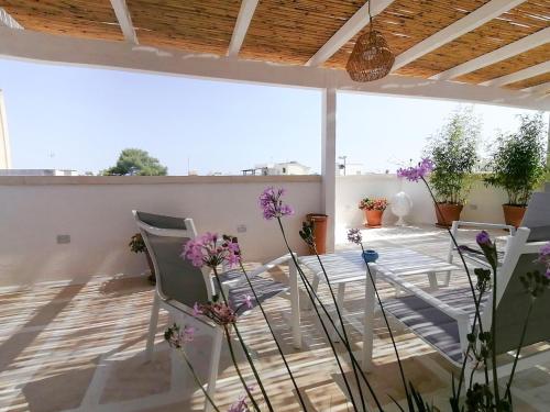 un patio con sedie e fiori sul balcone di Casa Flora - Bed and Breakfast a Torre San Giovanni Ugento