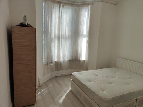 1 dormitorio con cama blanca y ventana en Millais Road en Londres