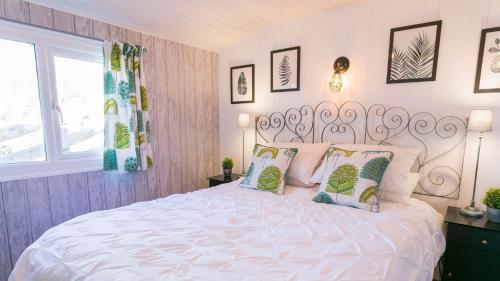 una camera da letto con un letto bianco con cuscini e una finestra di Easter Cabin a Moelfre