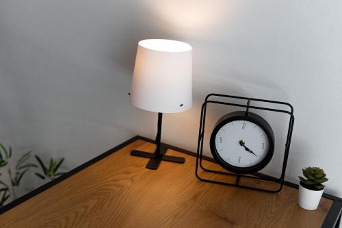 a lamp and a clock on a wooden table at Beautiful Apartments With Parking In a Quiet Location in Ostrava