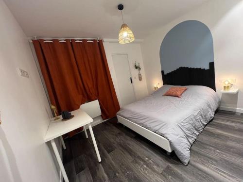 Schlafzimmer mit einem Bett, einem Tisch und einem Spiegel in der Unterkunft Appartement cosy proche du centre in Reims