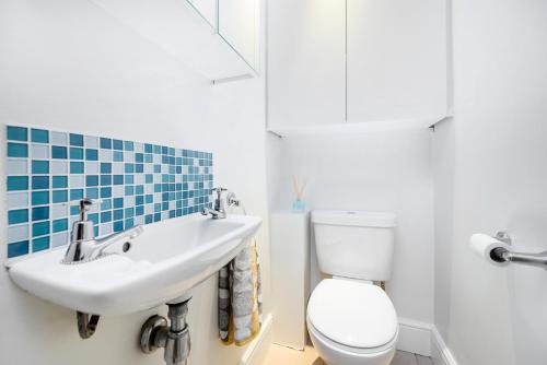 y baño con aseo blanco y lavamanos. en Modern 3 bedroom house with garden view, en Londres