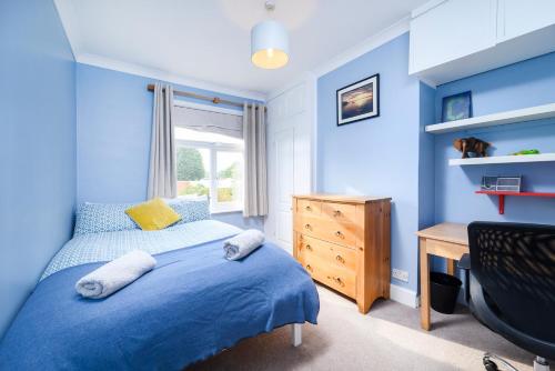 ロンドンにあるModern 3 bedroom house with garden viewの青い壁のベッドルーム1室、ベッド1台、デスクが備わります。