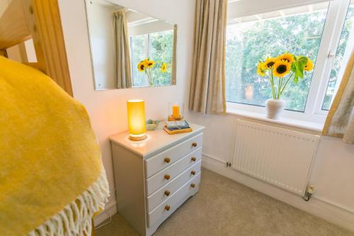 ein Schlafzimmer mit einer Kommode und einem Fenster mit Sonnenblumen in der Unterkunft Min y Wygyr in Cemaes Bay