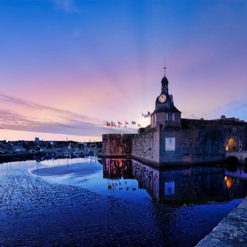 a building with a clock tower next to a body of water at Cœur de Concarneau, appartement entier, proche centre, corniche et plage avec parking in Concarneau