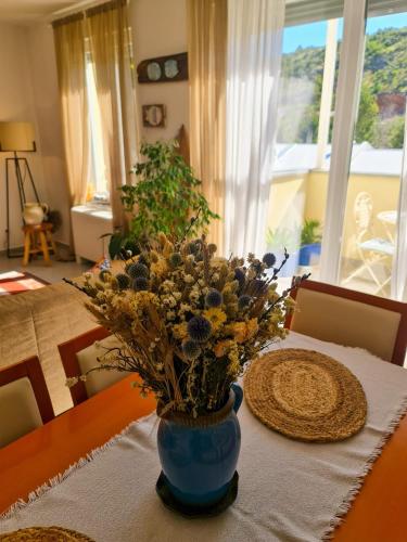 a table with a blue vase with flowers on it at Apartment TORRE - NEW in Senj