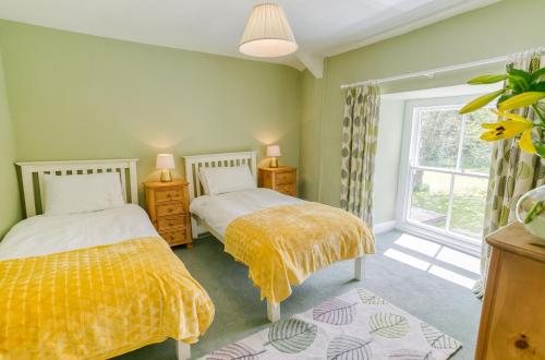 two beds in a room with a window at Plas Lligwy Cottage in Moelfre