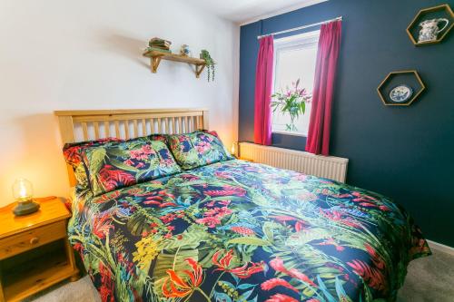 a bedroom with a colorful bed and a window at Dinas Cottage in Benllech