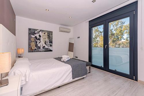 sypialnia z białym łóżkiem i dużym oknem w obiekcie Beach Villa Cosins 1 Mel w Alcudii