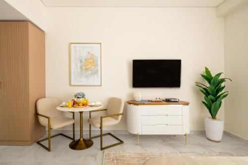 a living room with a table and a tv on a wall at Happy ACADEMIA JBR in Dubai